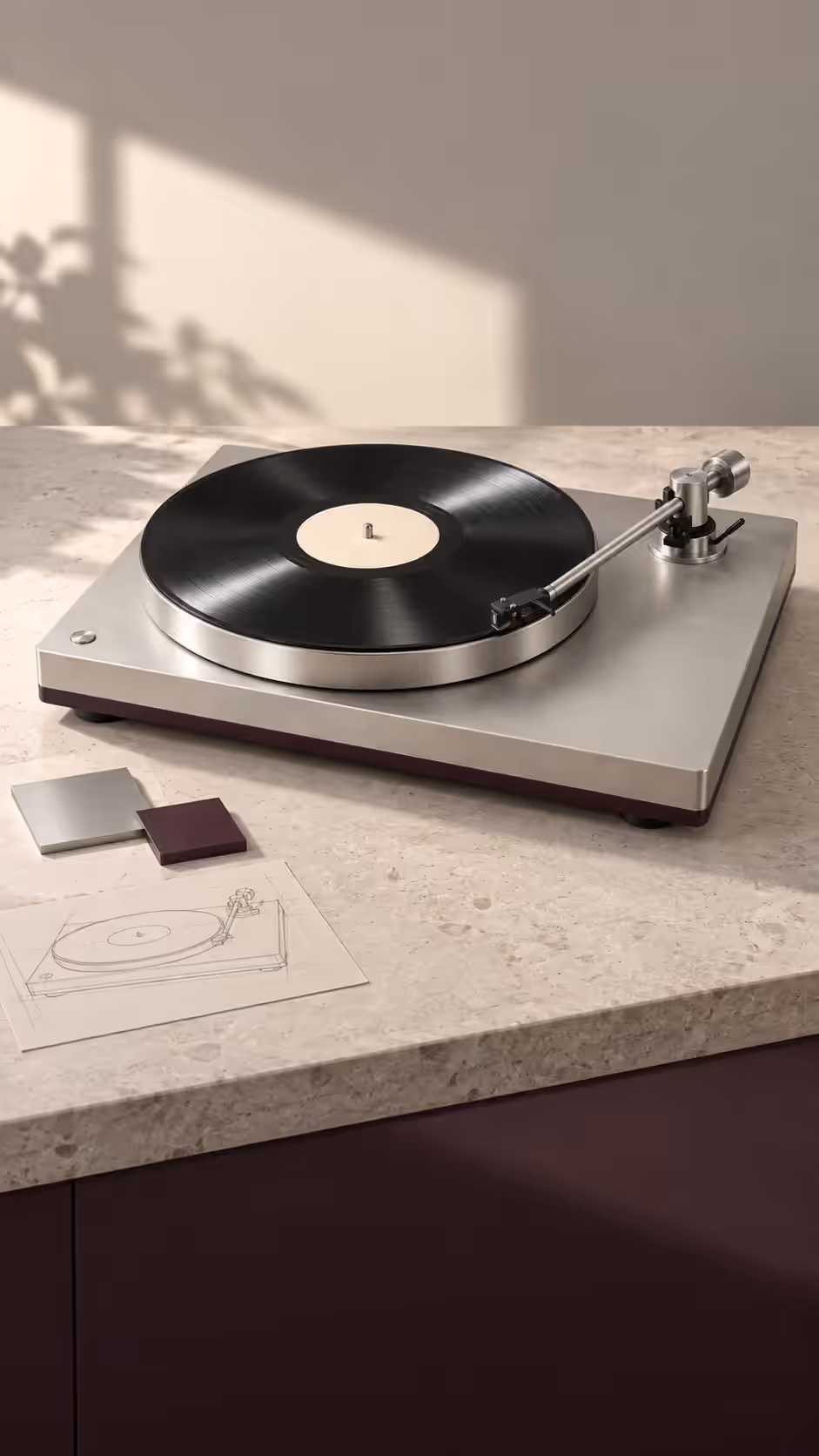 The turntable on a stone kitchen counter in soft daylight beside material swatches and a sketch