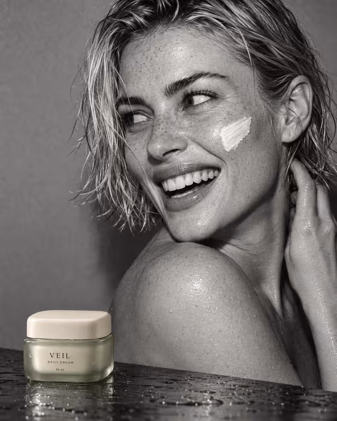 A black and white portrait of a smiling woman with a cream stripe on her cheek beside a VEIL jar